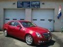 Red sedan parked in front of a garage with blue signs above the doors.