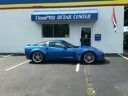 Blue sports car parked outside a building with a sign reading “Classic AUTO CENTER”