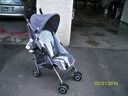 Gray stroller parked on a wet sidewalk beside a building entrance