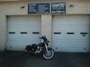 Motorcycle parked in front of two white garage doors with signs above them