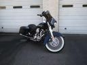 Black motorcycle parked on a gray surface, viewed from the side with chrome details