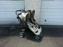 Folded black-and-white stroller standing on a driveway in front of a garage door