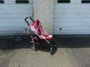 Red and white stroller parked beside a garage door on pavement