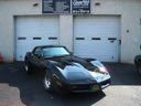 Black sports car parked in front of a garage with two white doors