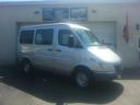 White van parked indoors in a garage or showroom, side view with front angled right.
