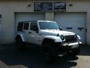 White Jeep SUV parked in a driveway beside a building