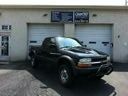 Black pickup truck parked outside a garage with white doors and blue signs