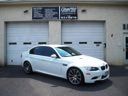 White sedan parked in front of a gray garage with closed doors