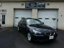 Black sedan parked in front of a garage with closed white doors