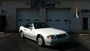 White convertible sports car parked in front of a building with garage doors