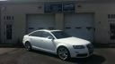 White sedan parked outside a building in bright sunlight