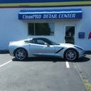 Silver sports car parked outside a repair center building.