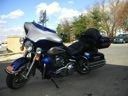 Two parked motorcycles, one blue and one black, on a sidewalk near buildings