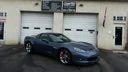 Blue sports car parked in front of a white garage building with brown doors
