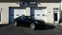Black sports coupe parked in front of a beige garage building with white doors