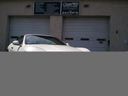 White car parked in front of a beige garage door