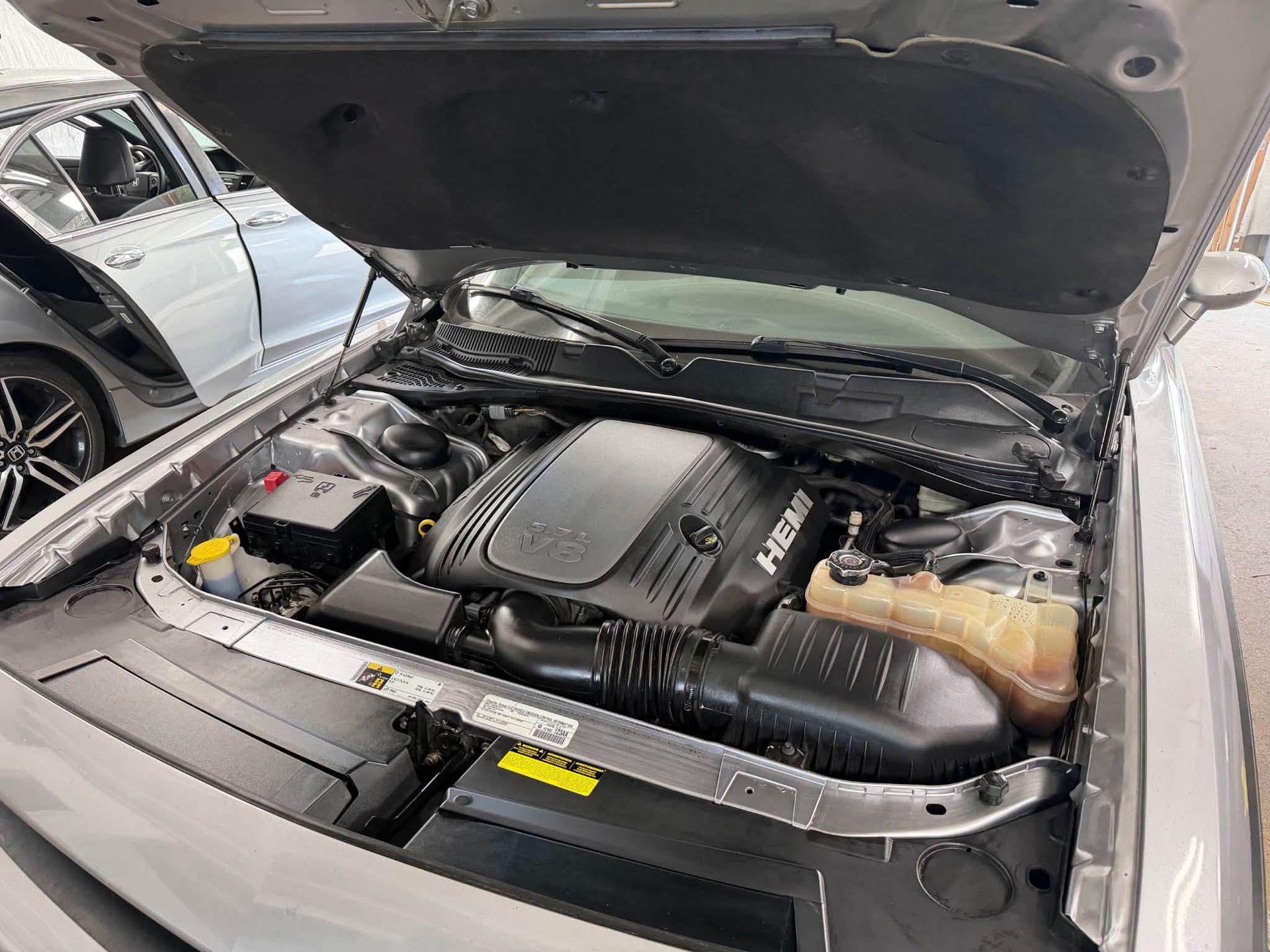 Open car hood showing engine bay with Hyundai engine cover and black plastic components