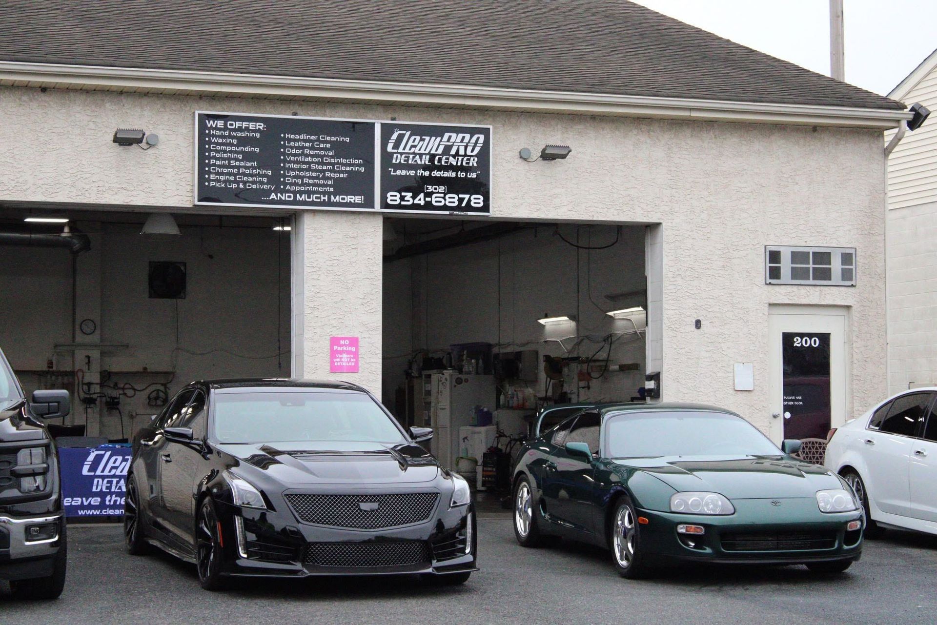 Two sports cars parked outside an auto shop garage