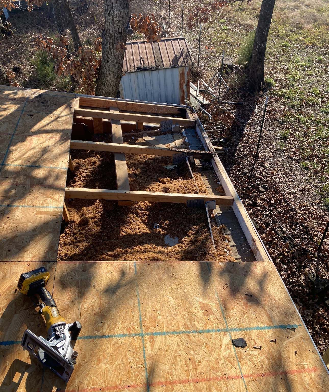 Construction site with a section of floor framing exposed on a wooden deck next to a circular saw.