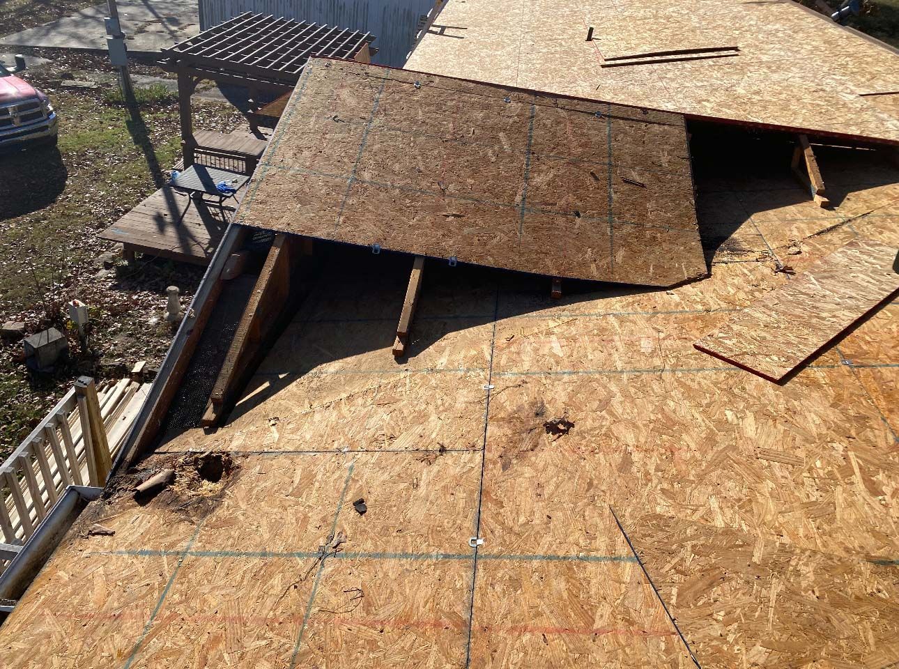 A section of OSB roof sheathing is missing, exposing the interior roof framing above a house under construction.