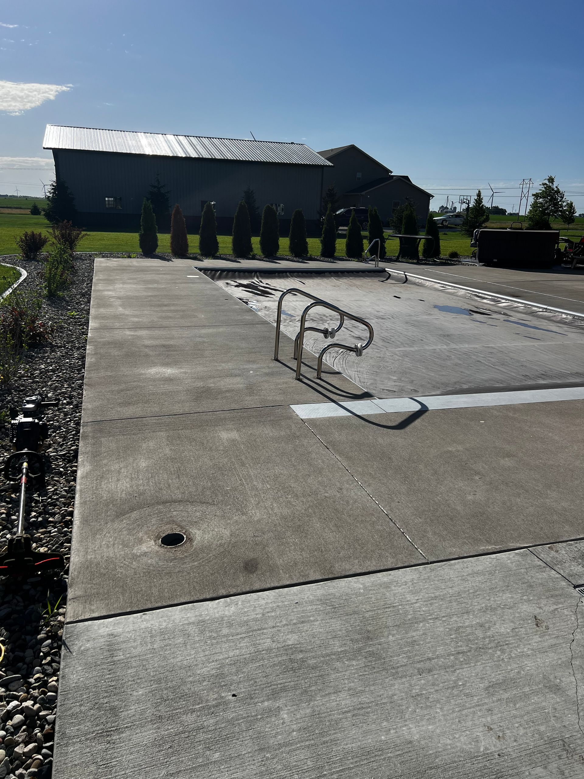 A concrete driveway with a broken railing and a house in the background
