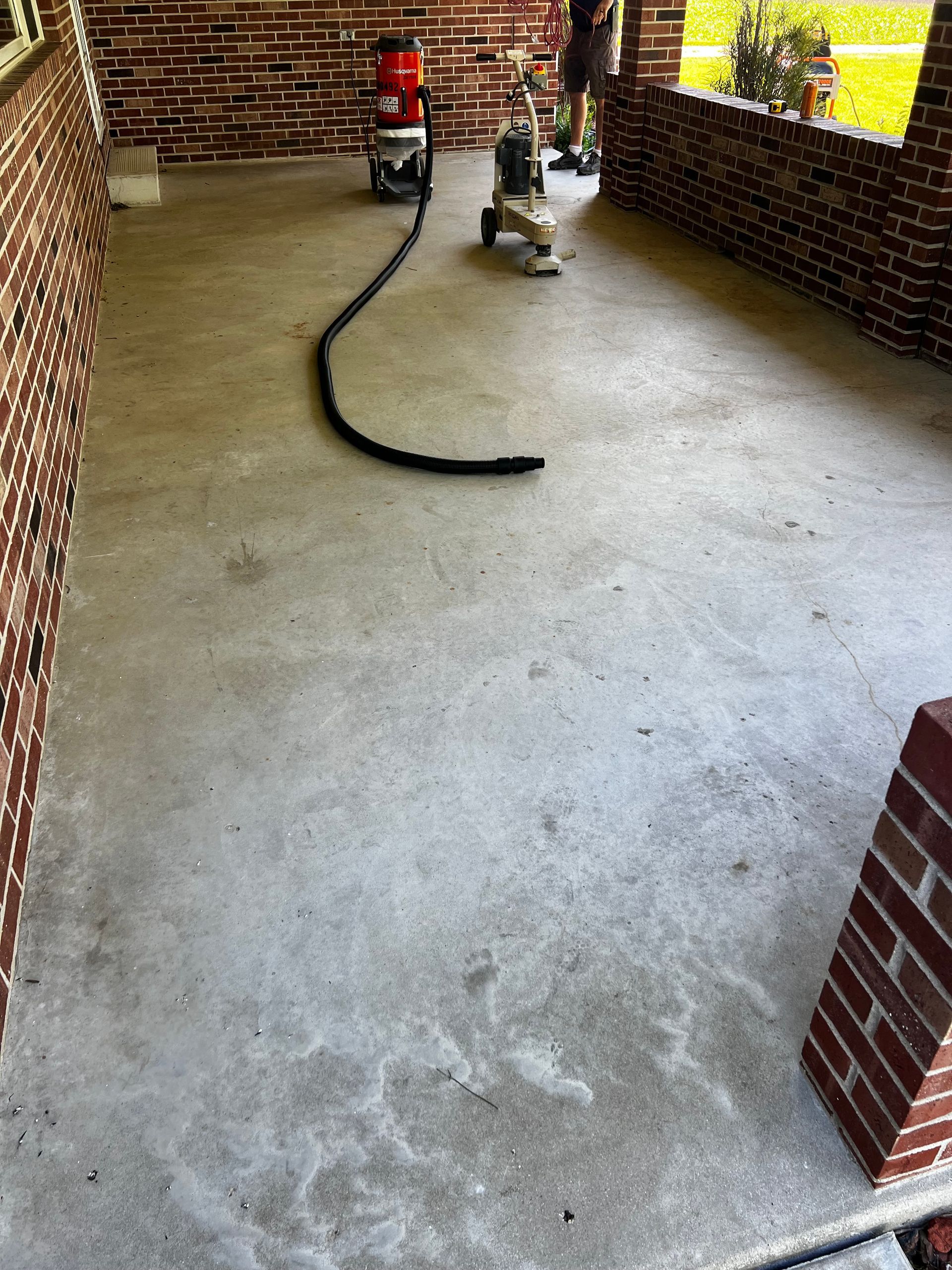 A vacuum cleaner is sitting on a concrete floor next to a brick wall.
