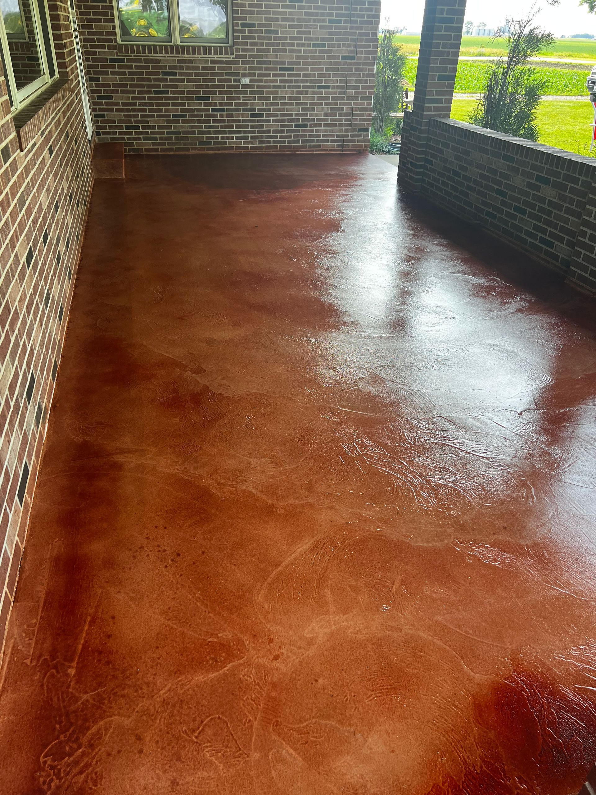A brick porch with a red concrete floor and a brick wall.