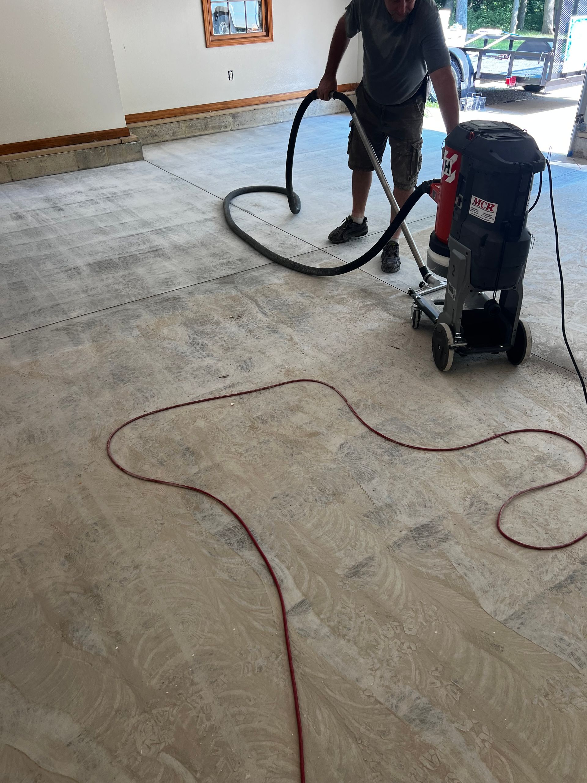 A man is using a vacuum cleaner to clean a garage floor.