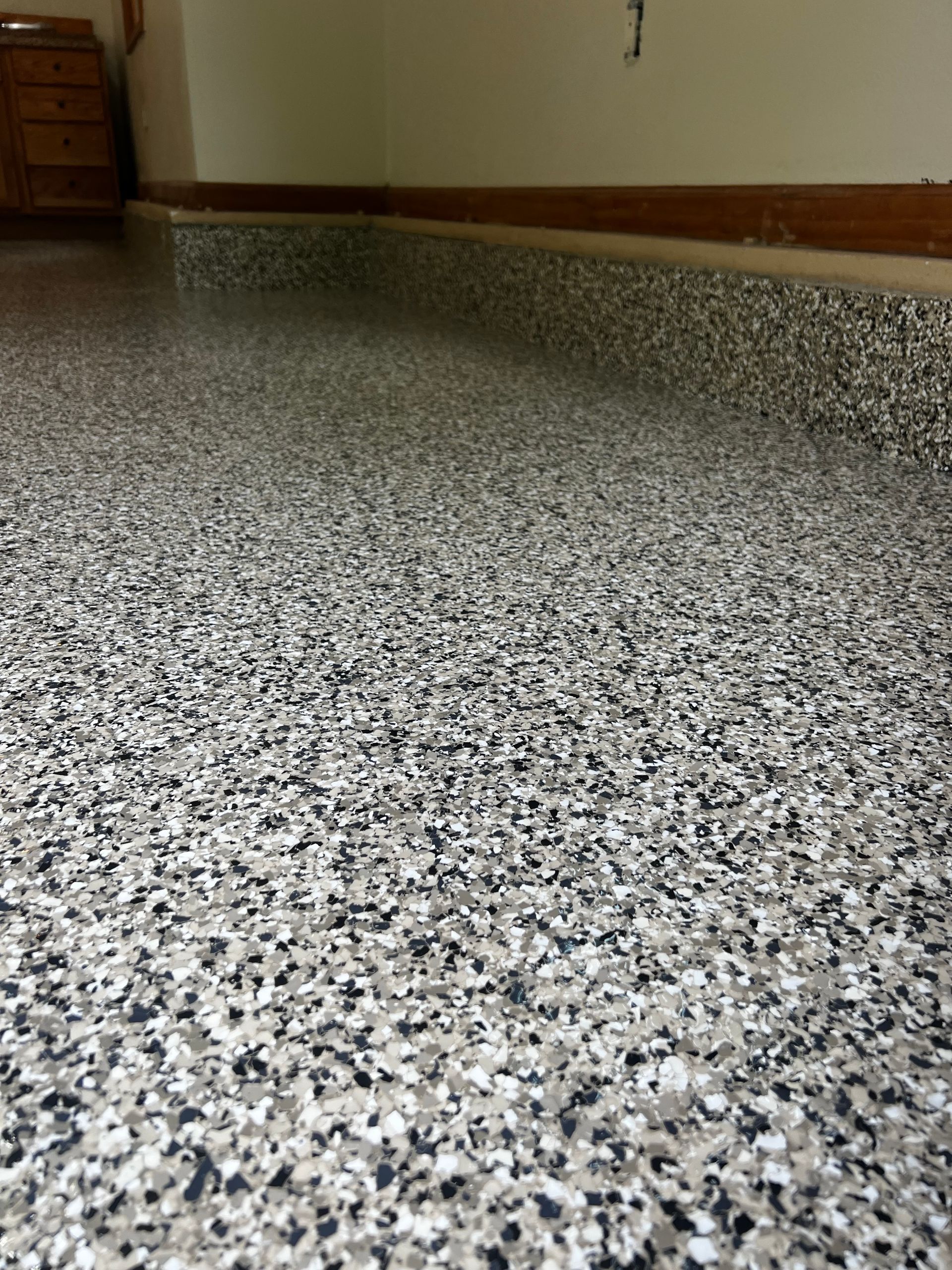 Garage floor with speckled epoxy coating in shades of gray, white, and black.