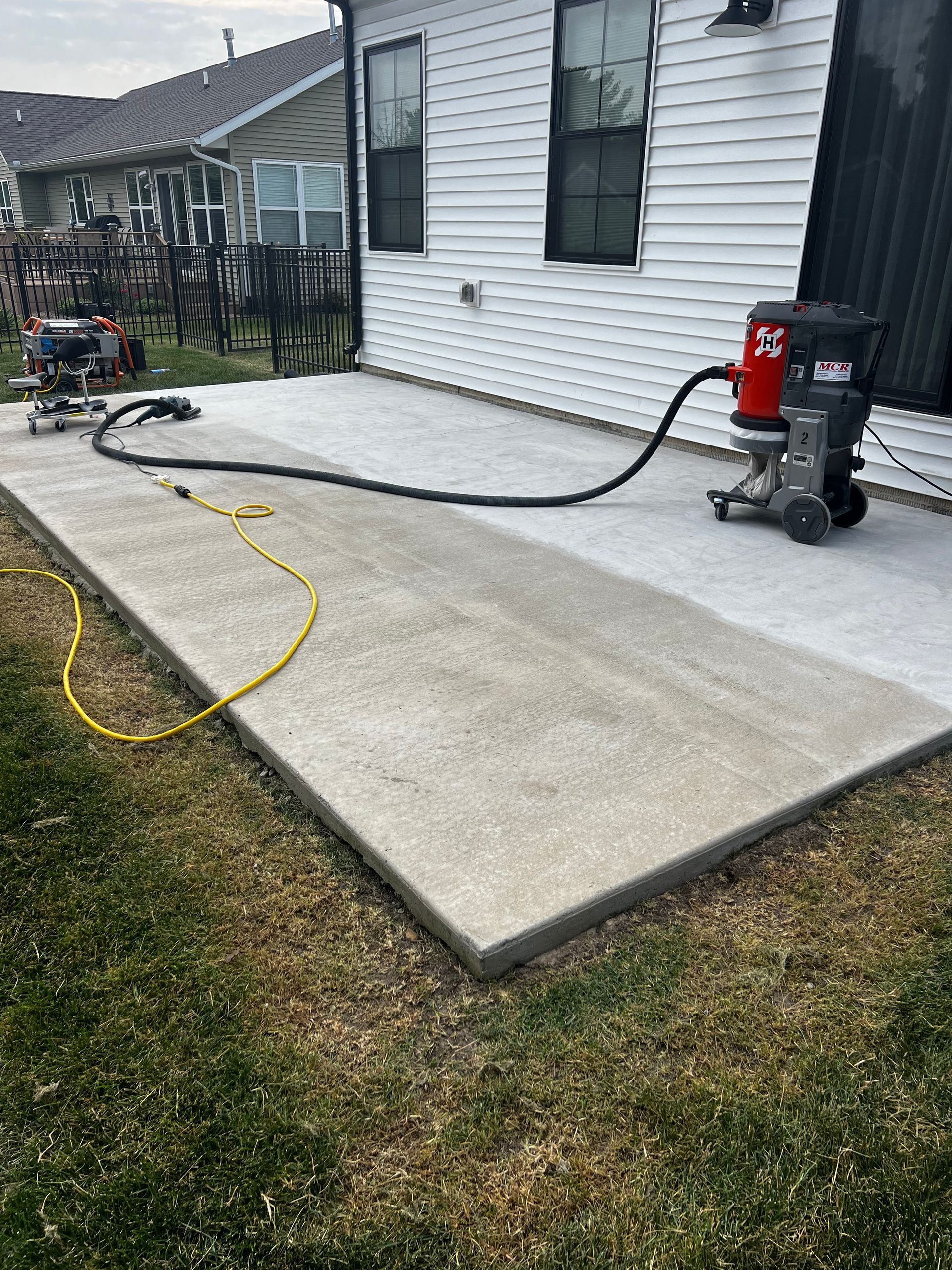 A vacuum cleaner is sitting on a concrete patio in front of a house.