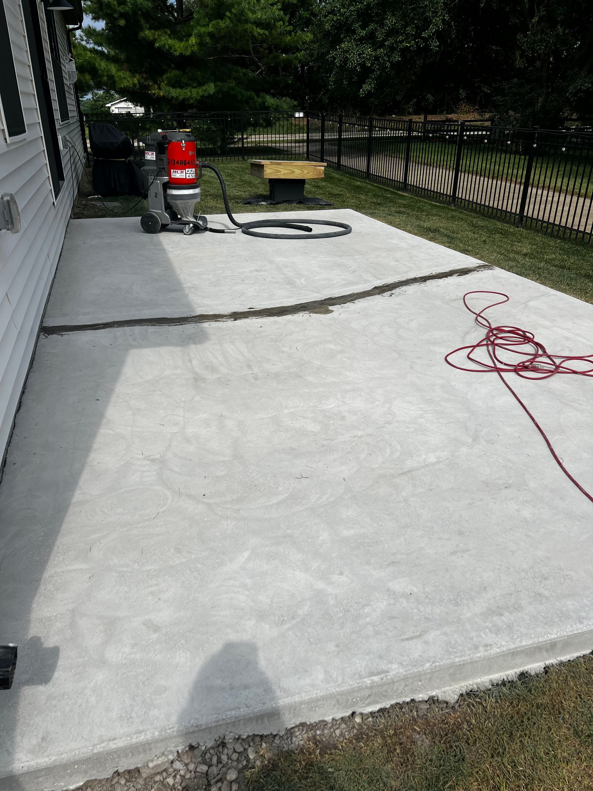 A vacuum cleaner is sitting on a concrete patio next to a house.