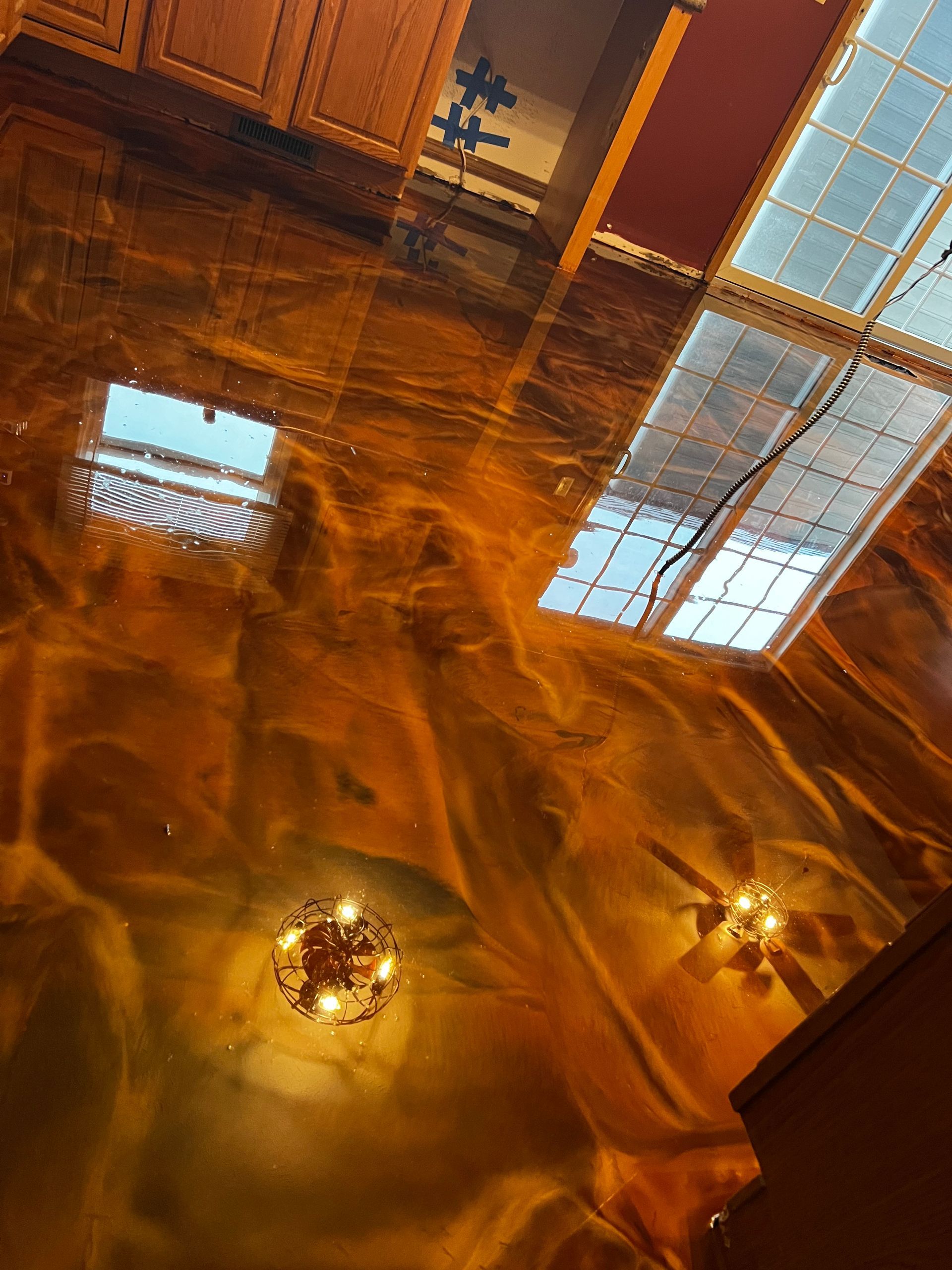 A kitchen with a shiny gold floor and a chandelier hanging from the ceiling.