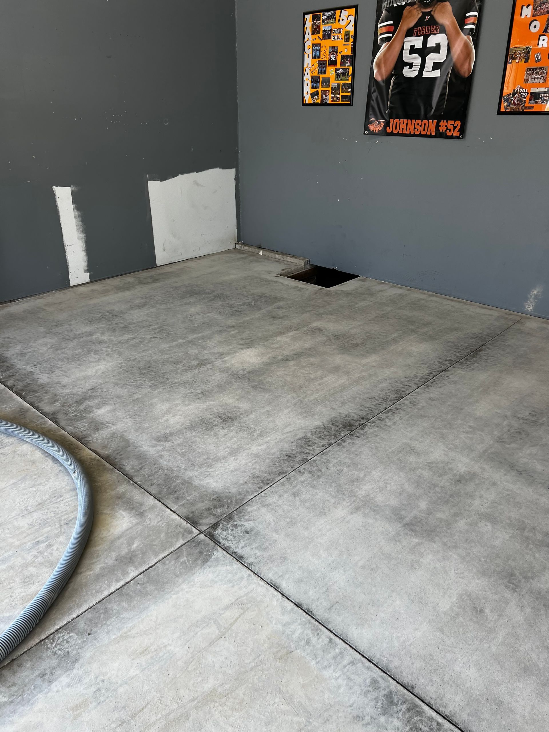 A concrete floor in a room with posters on the wall.
