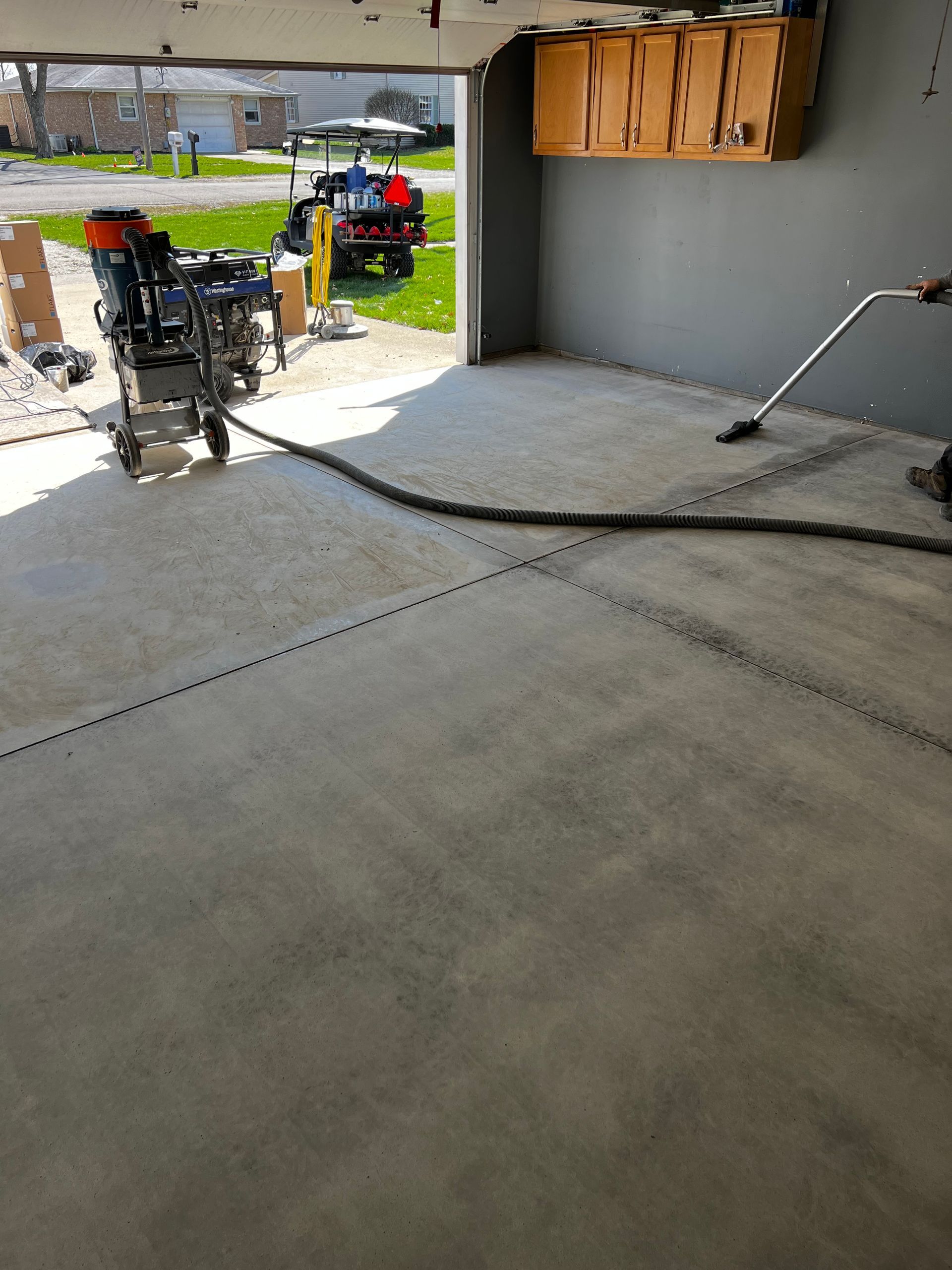 A vacuum is being used to clean a concrete floor in a garage