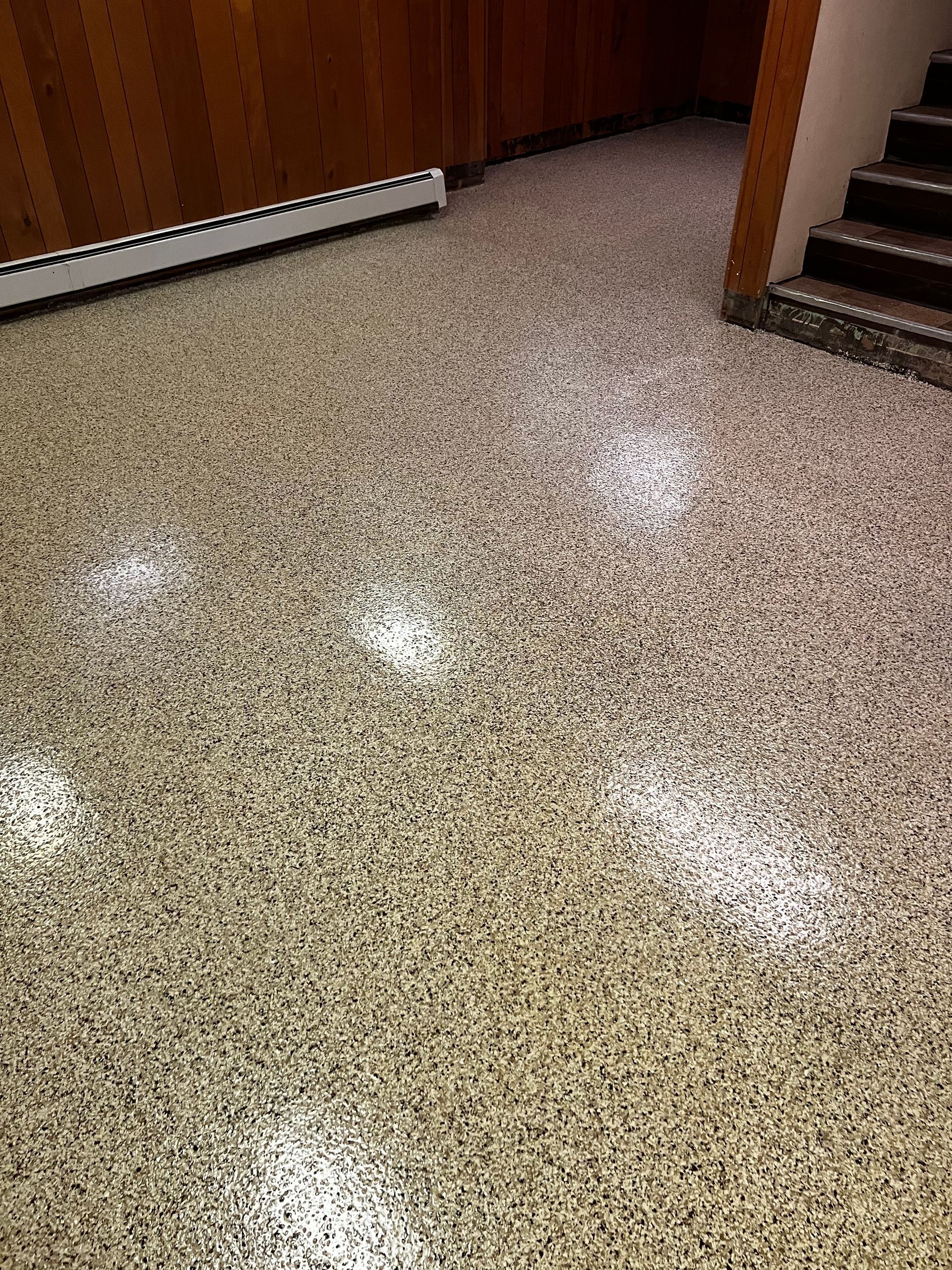 A close up of a shiny floor with stairs in the background.