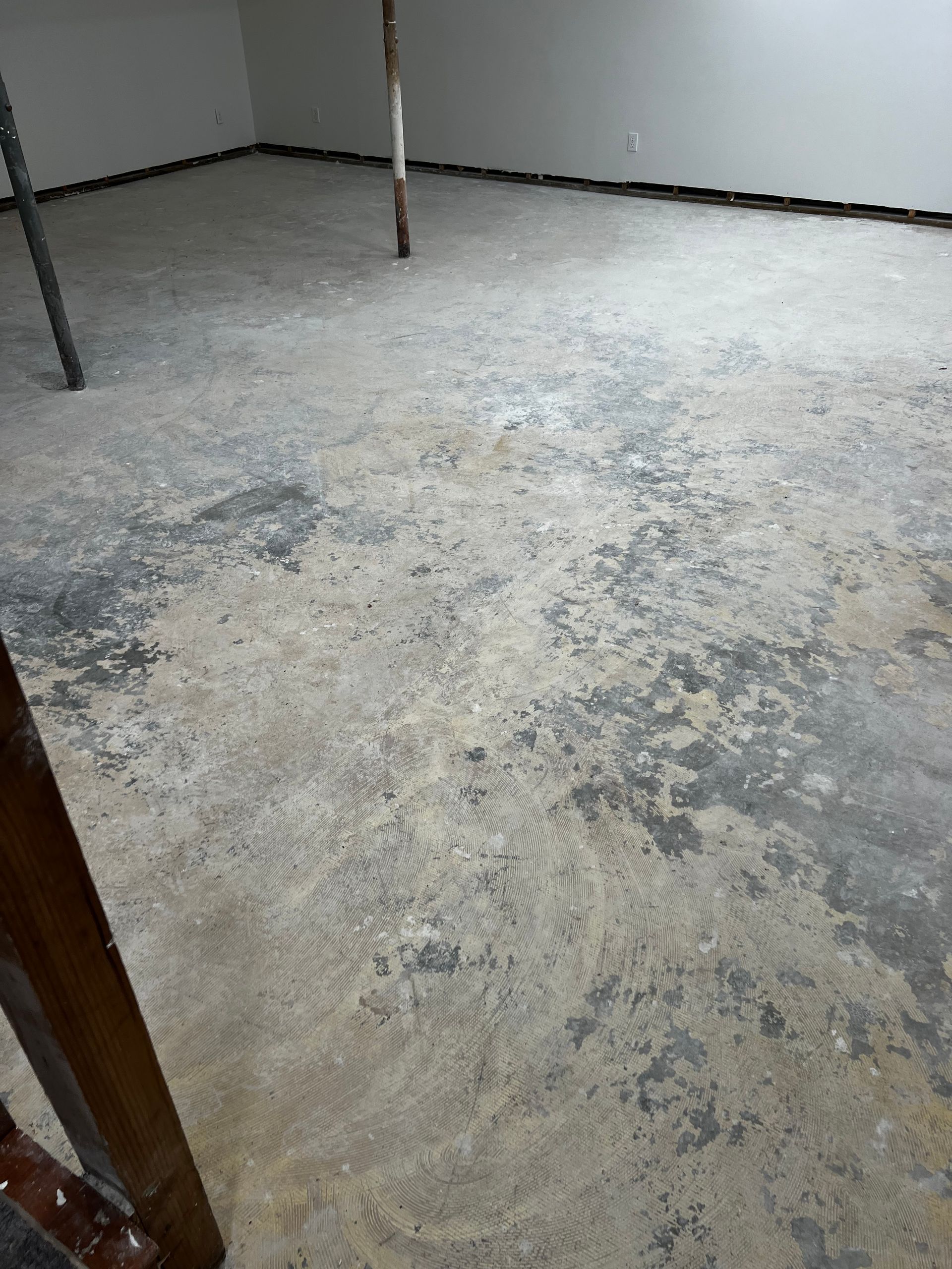 A room with a concrete floor and a wooden staircase.