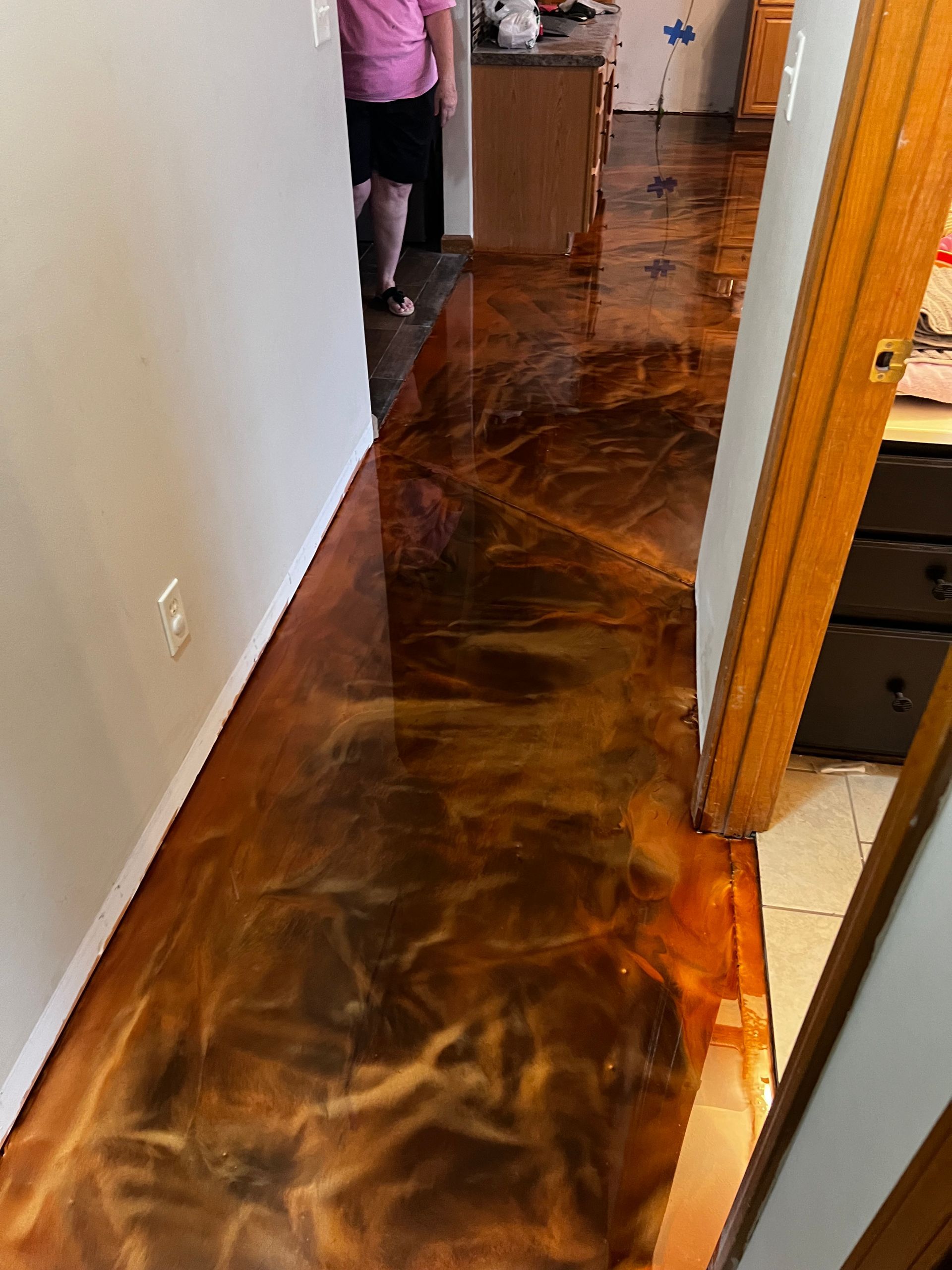 A woman is standing in a hallway with a metallic floor.