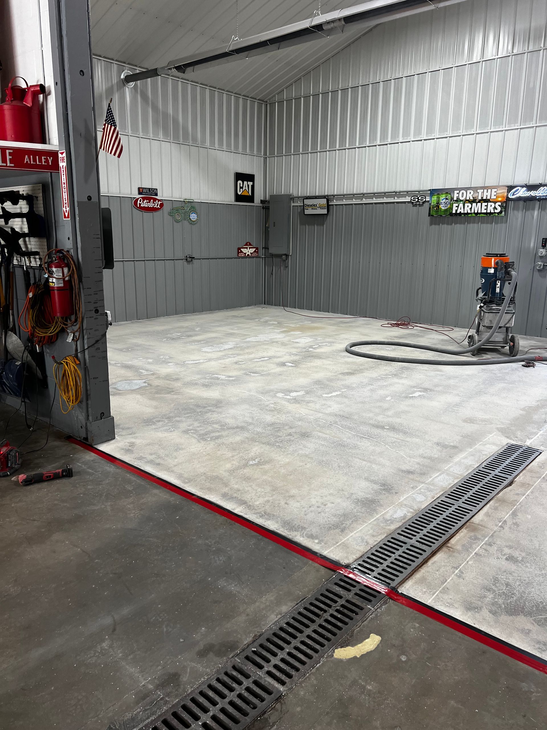 A garage with a vacuum cleaner on the floor and a drain.