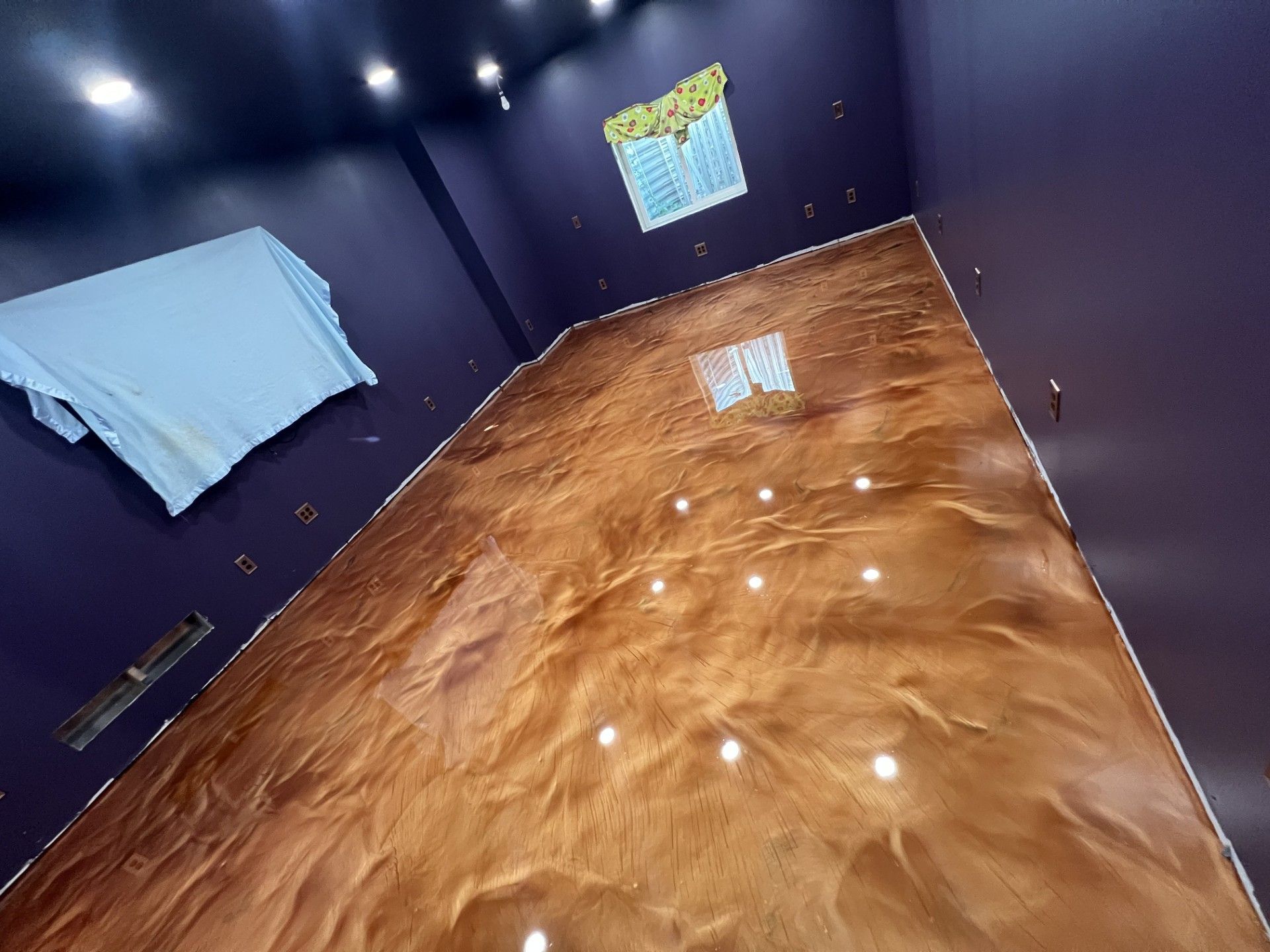 Room with metallic bronze epoxy floor, dark purple walls, and bright overhead lights.
