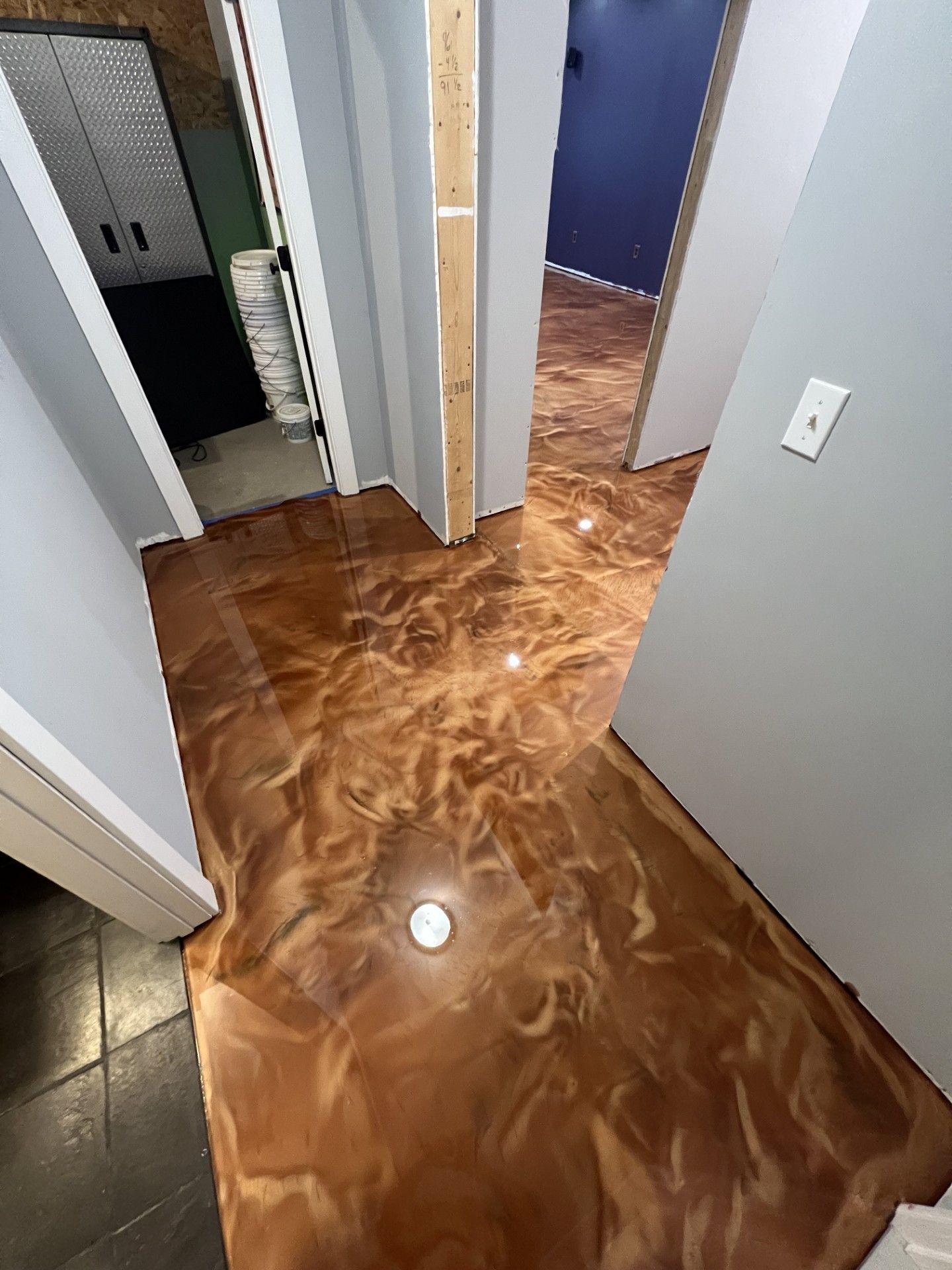 Metallic epoxy floor in hallway, brown and gold swirls, with doors to rooms and cabinets.