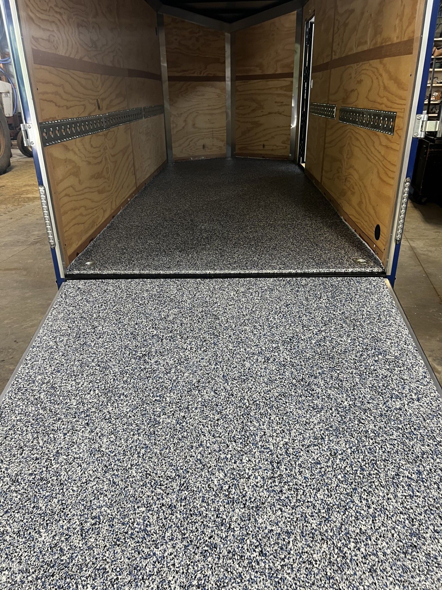 Interior of an open cargo trailer with an epoxy floor and ramp