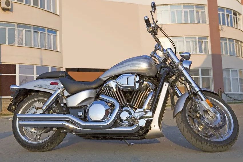 A silver motorcycle is parked in front of a building
