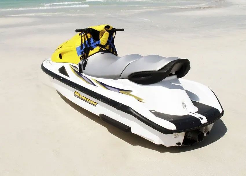 A yellow and white jet ski is parked on the beach