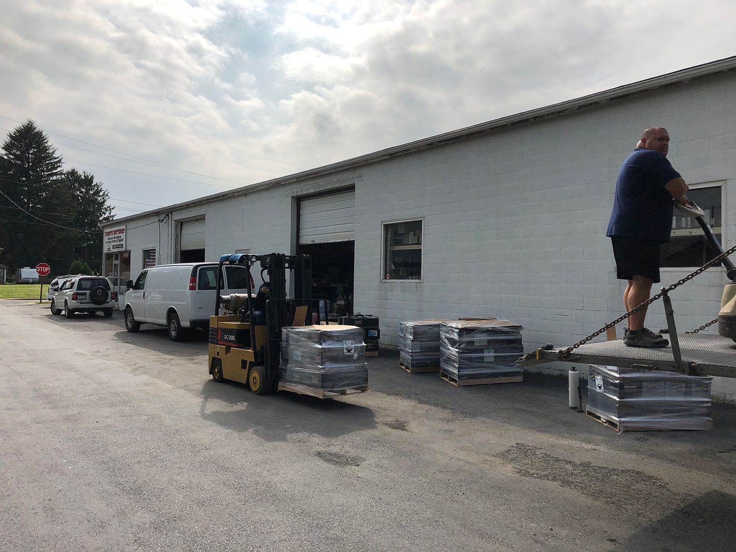 A man is standing next to a forklift in front of a building.