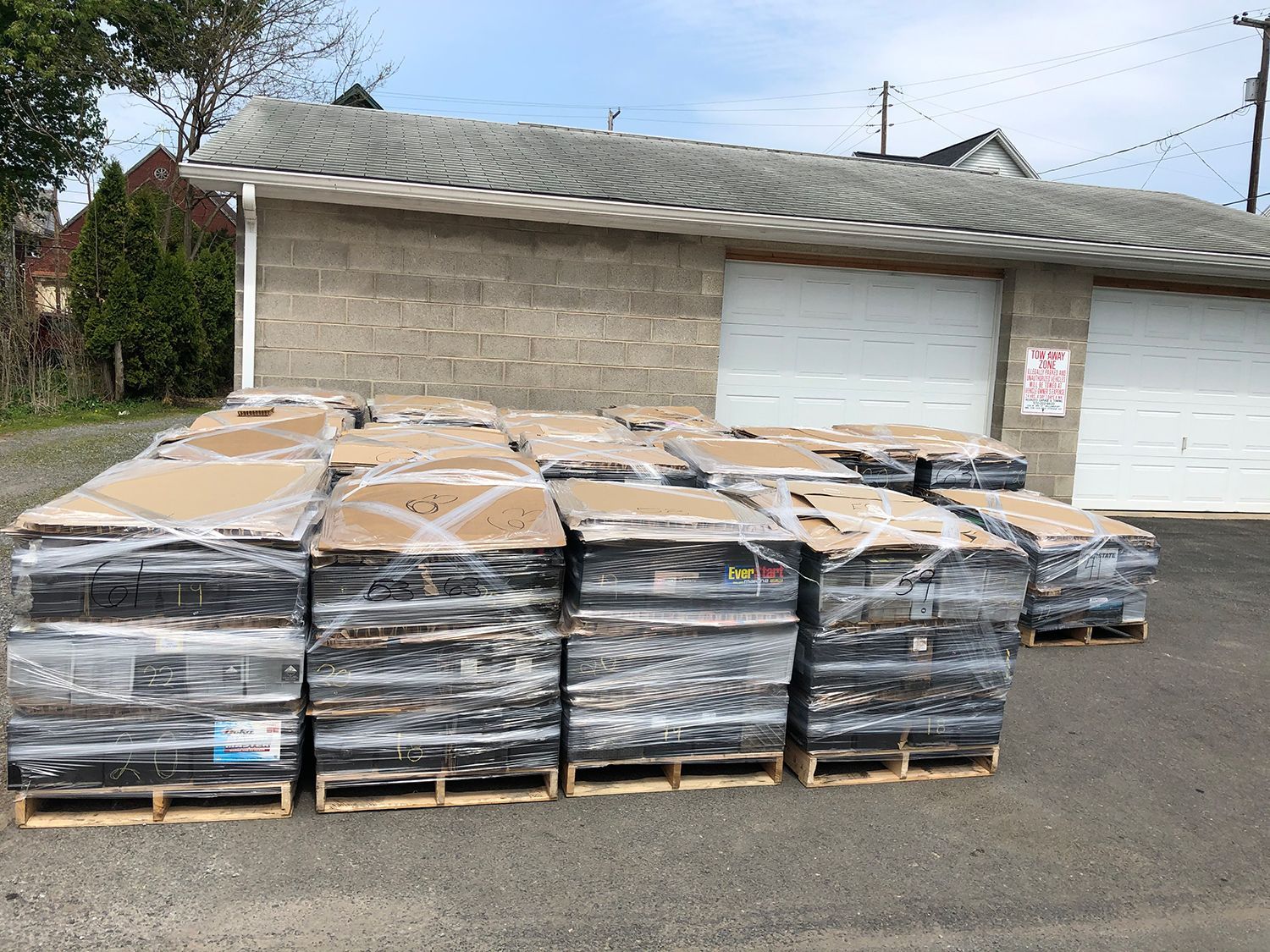 A bunch of pallets are stacked on top of each other in front of a garage.