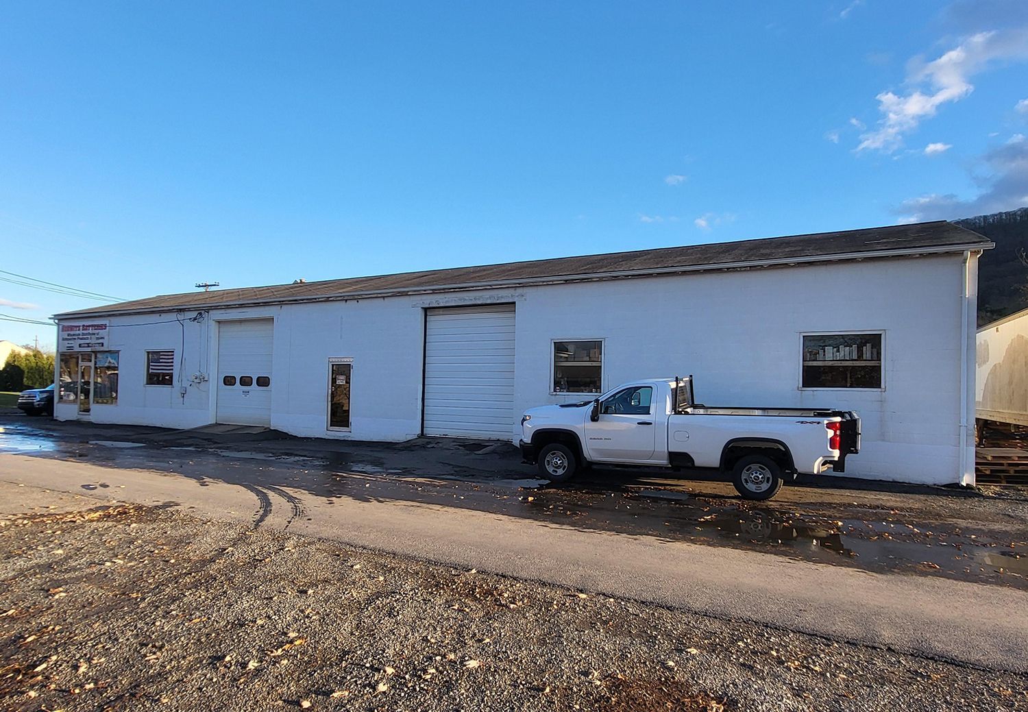 A white truck is parked in front of a white building.