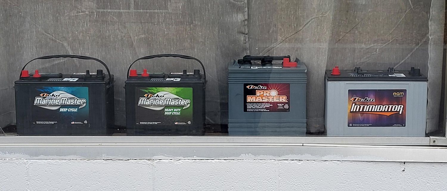 Four different types of batteries are lined up on a shelf.
