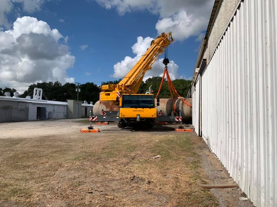 A large yellow crane is parked in front of a building under construction.