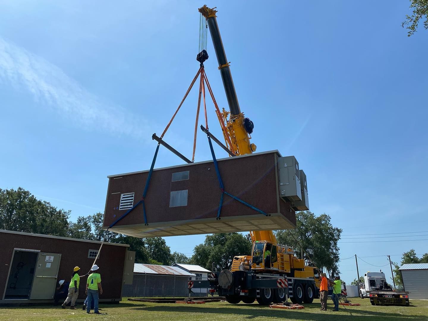 A crane is lifting a brick building into the air.
