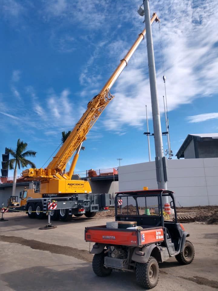 A yellow crane is sitting on top of a pole next to a red vehicle